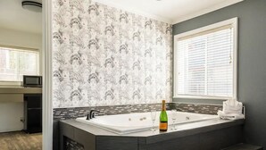 Ein modernes Badezimmer mit einer großen Badewanne, einem Waschbecken mit Spiegel und einem Fenster mit Jalousien.