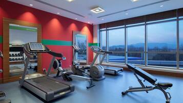 Un gimnasio con cintas de correr, elípticas y una prensa de banca.
