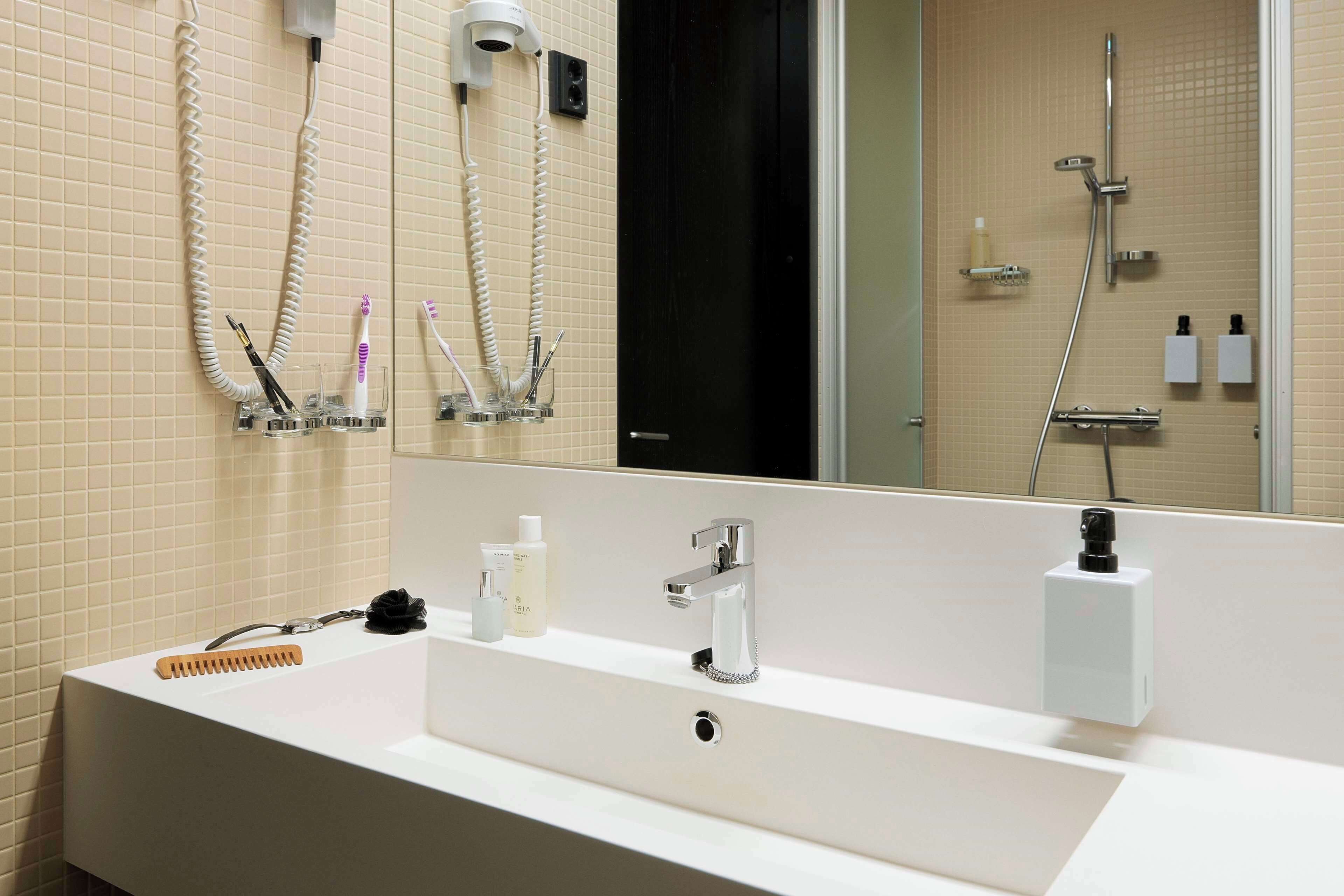 Un bany modern amb un lavabo gran, un mirall i una dutxa.