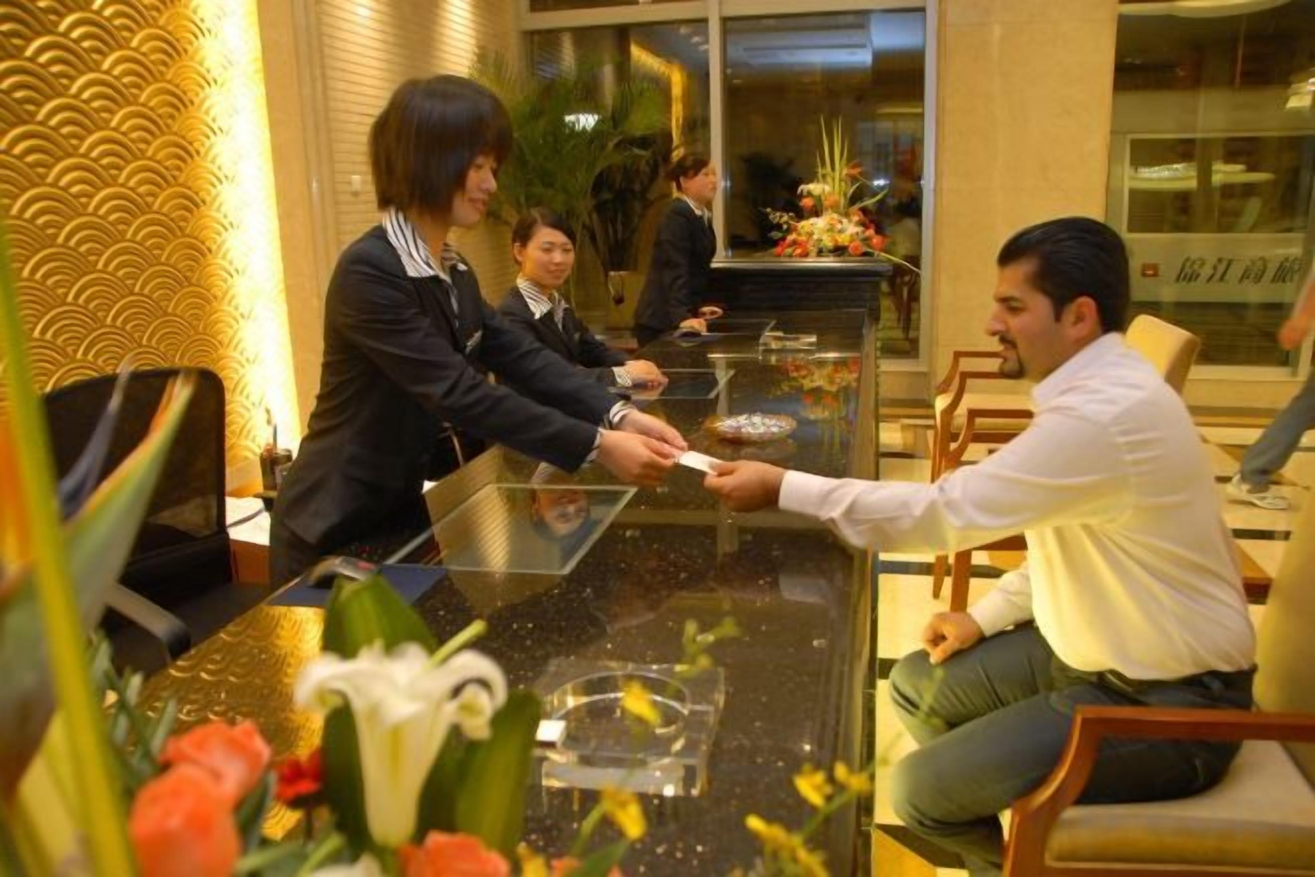 A hotel reception area with a reception desk, chairs, and a counter.