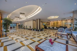 Vestíbulo de hotel con mostrador de recepción, zona de estar y escritorio de información.