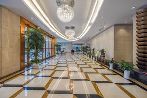 A hotel lobby with a checkered floor, large windows, and a chandelier.