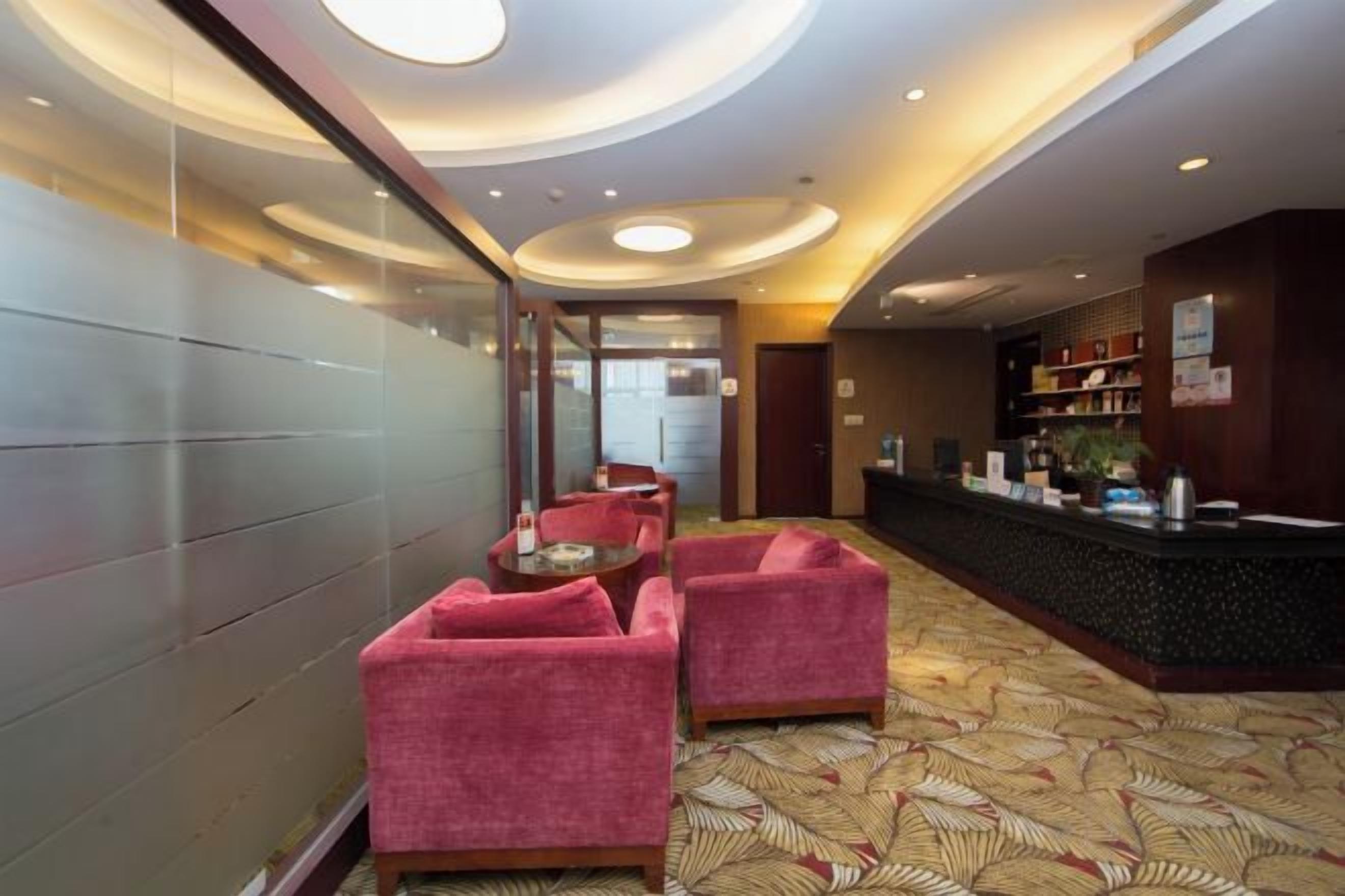 A hotel lobby with a reception desk, seating area, and a patterned carpet.