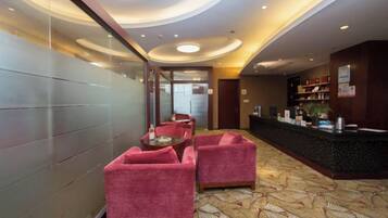 A hotel lobby with a reception desk, seating area, and a patterned carpet.