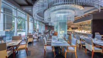 Un restaurante moderno con un comedor central, mesas largas y sillas.