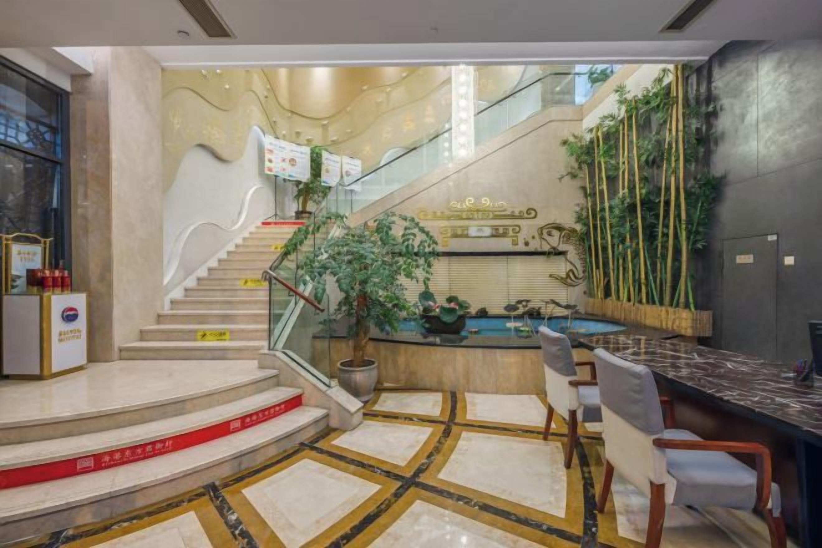 Un vestíbulo de hotel con una recepción, una escalera y una zona de piscina.