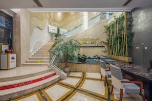 Un vestíbulo de hotel con una recepción, una escalera y una zona de piscina.