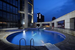 Una piscina al aire libre, sombrillas, sillones reclinables de piscina