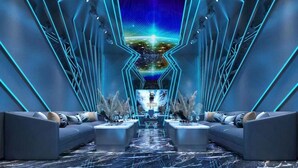 Un salón futurista con una mesa central, sofás y un techo iluminado con neón.