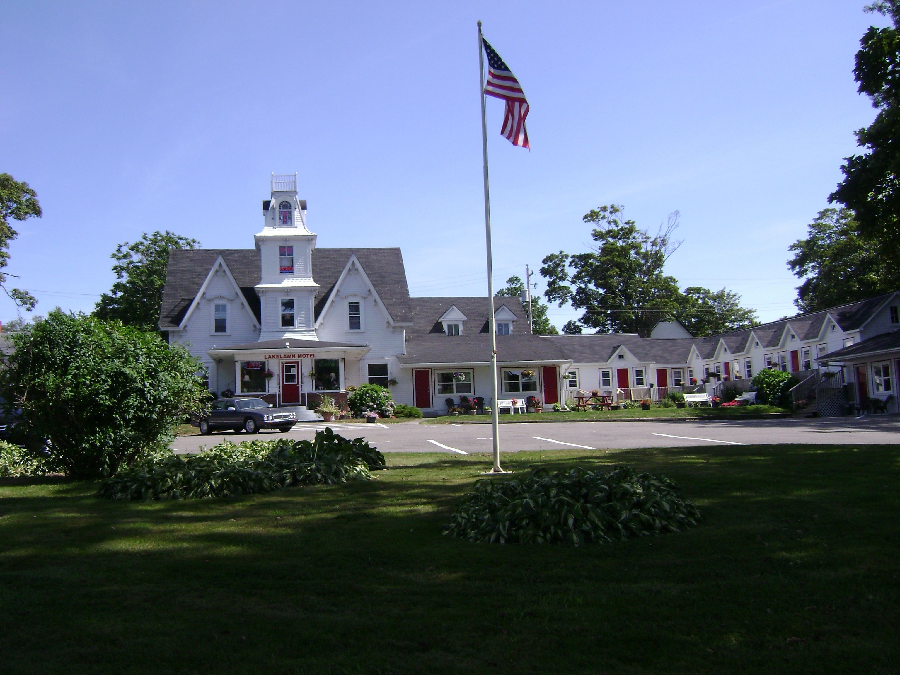 A white building with a red door and a flagpole with an American flag.