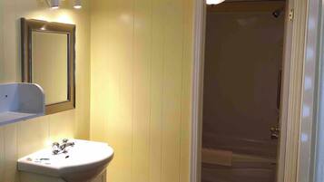 A bathroom with a white sink, a mirror, and a shower door.