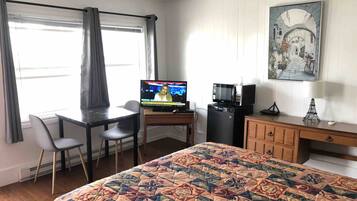Una habitación de hotel con cama, escritorio, televisor, microondas y un armario.