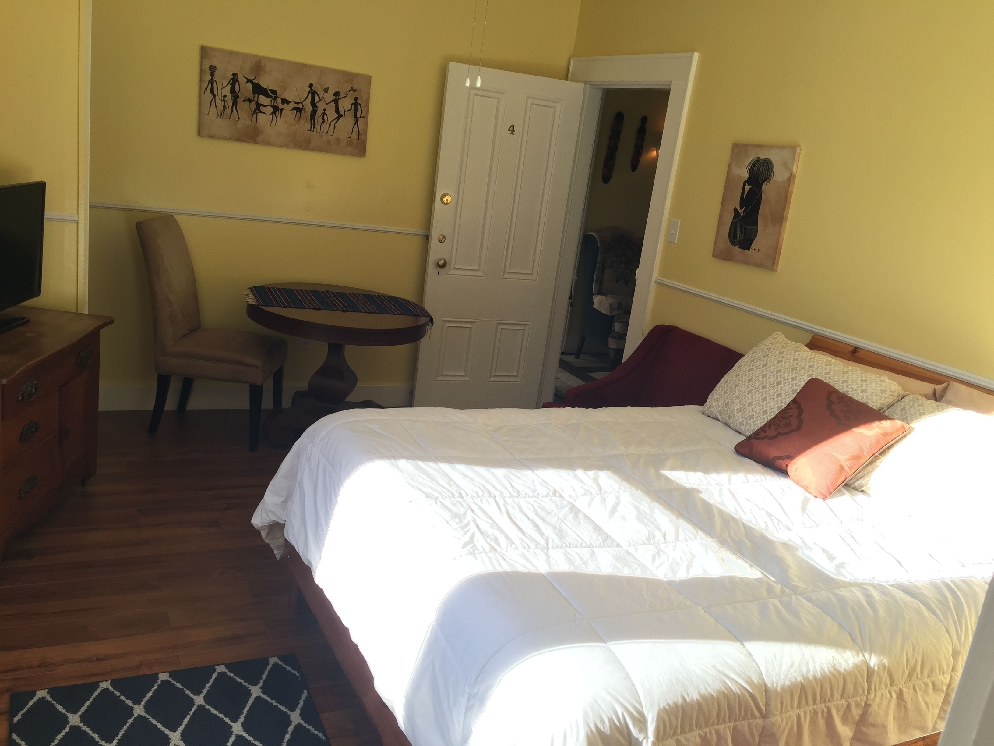 Un dormitorio con una cama, una silla, una mesita y un televisor.