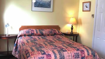 Ein Schlafzimmer mit Bett, Deckenventilator, Lampe, einem gerahmten Bild an der Wand und einer Tür.