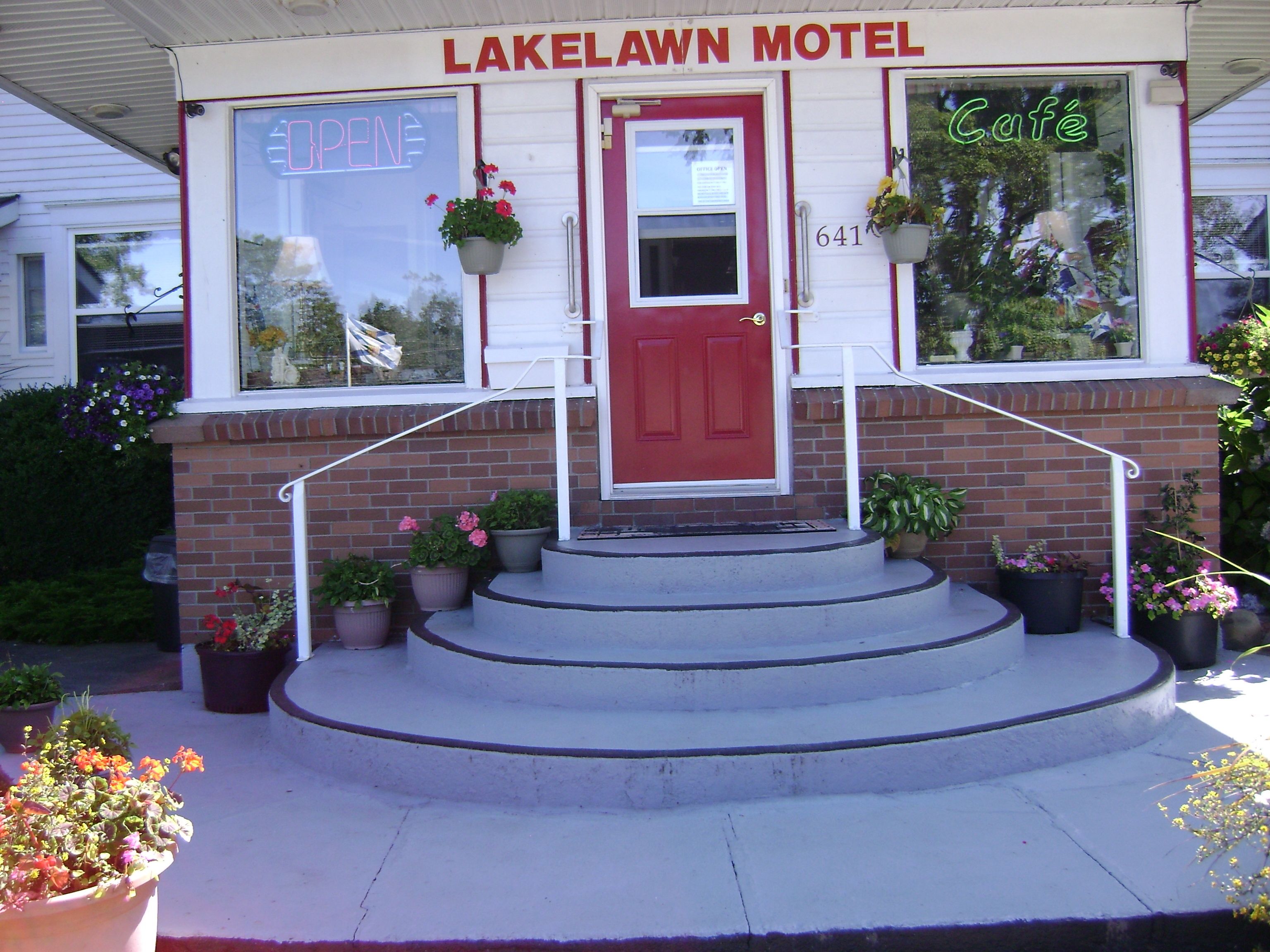 The exterior of Lakelawn Motel with a red door, a sign indicating it's open, and a 'Café' sign on the window.