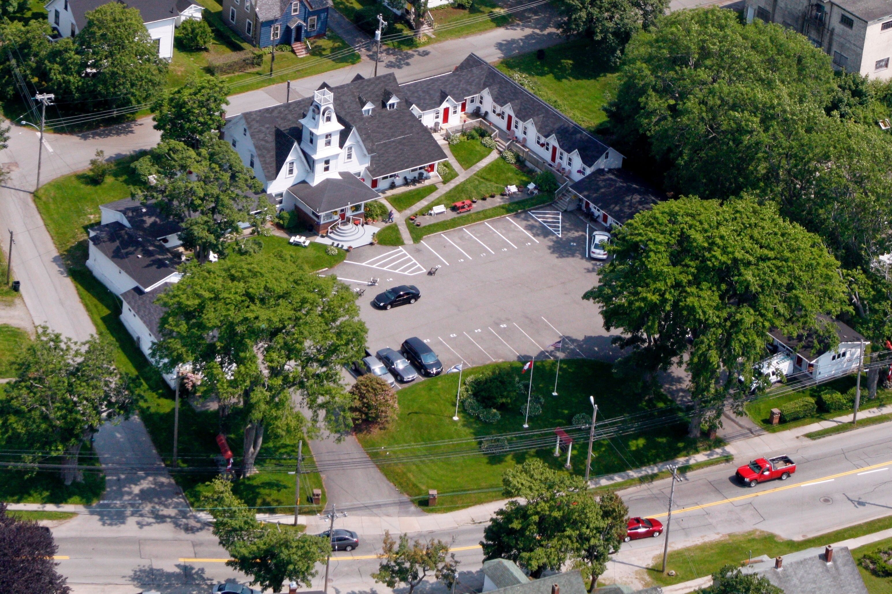 An aerial view of a church with a central steeple, parking lot, and surrounding greenery.