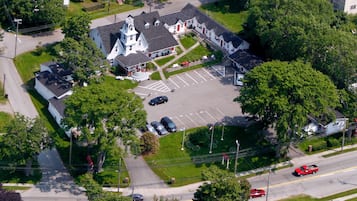 An aerial view of a church with a central steeple, parking lot, and surrounding greenery.