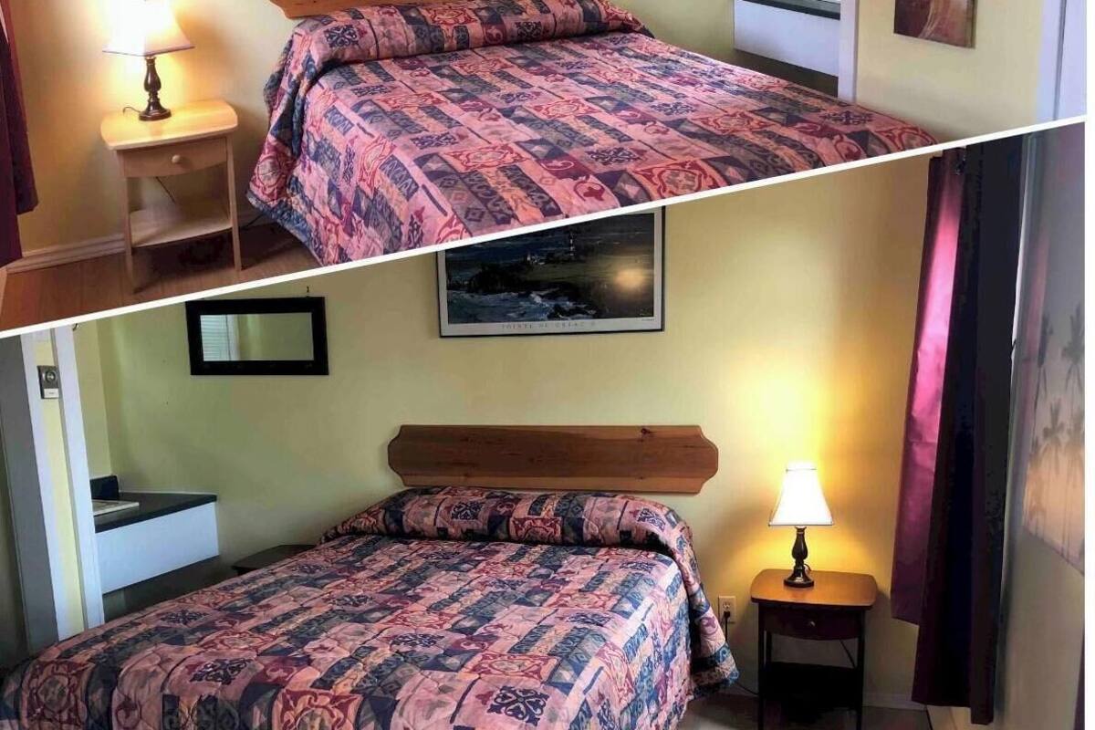 Une chambre à coucher avec un lit, une table de chevet, une lampe et une petite étagère sur laquelle est posée une photo.