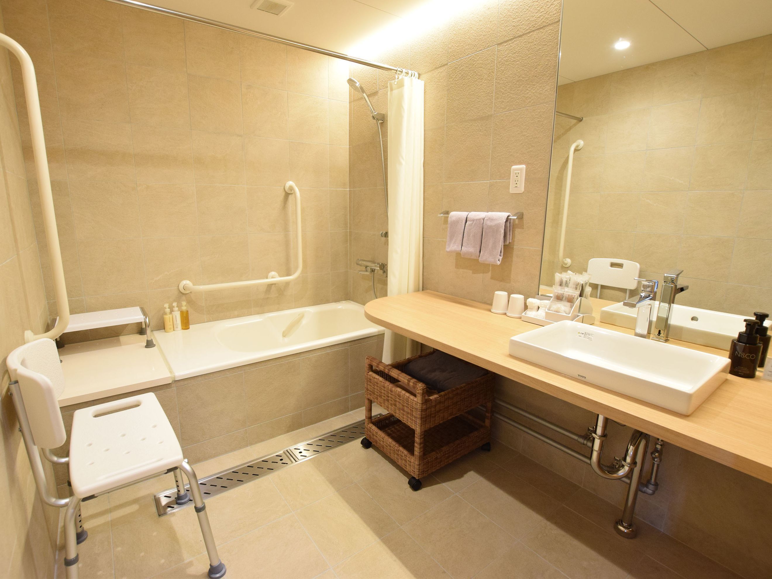 A modern bathroom with a bathtub, two sinks, a shower, and a wheelchair-accessible bench.