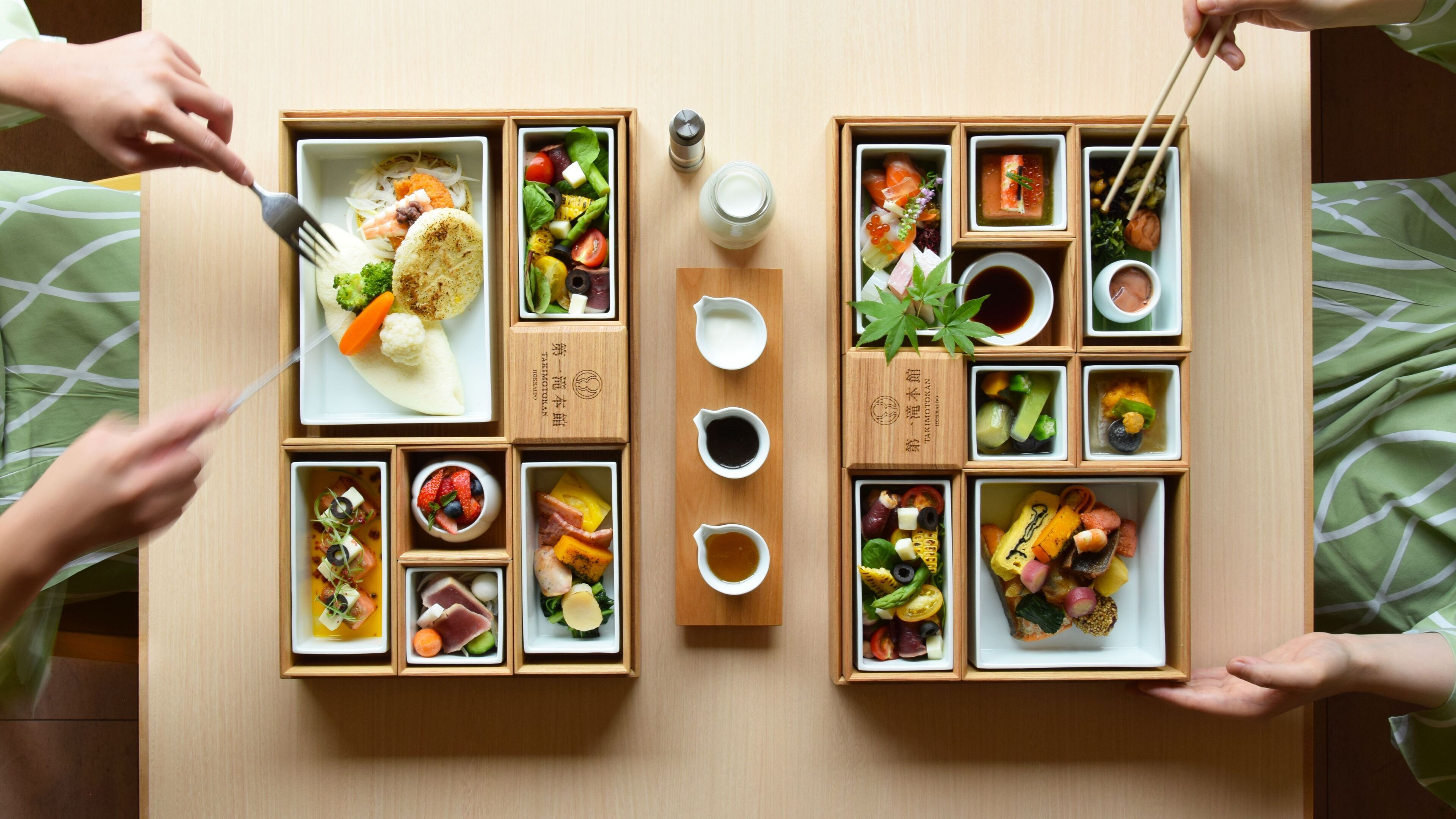 A wooden dining table with multiple compartments containing various dishes and condiments.
