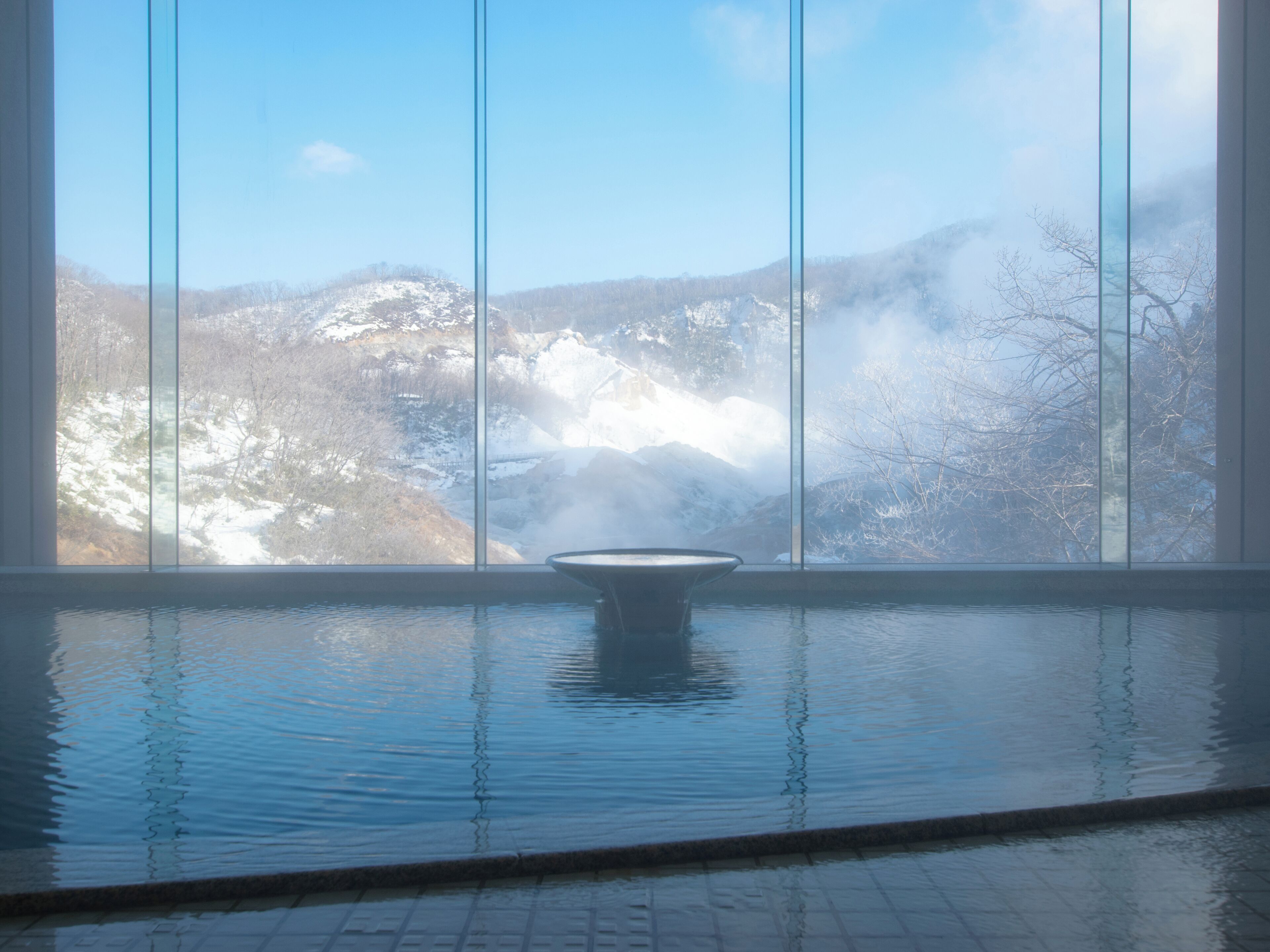 A spa pool with a view of snow-covered mountains through large windows.