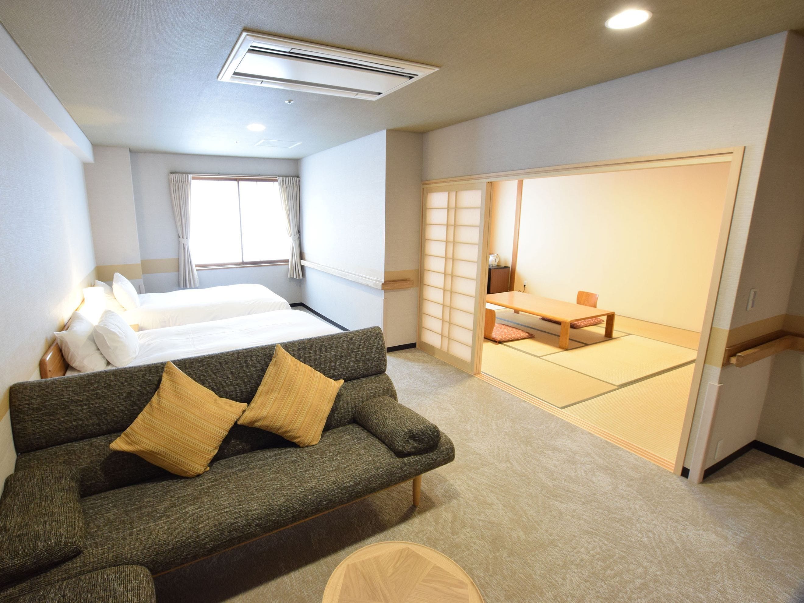 A hotel room with a bed, a sofa, a tatami mat area, and a sliding door.