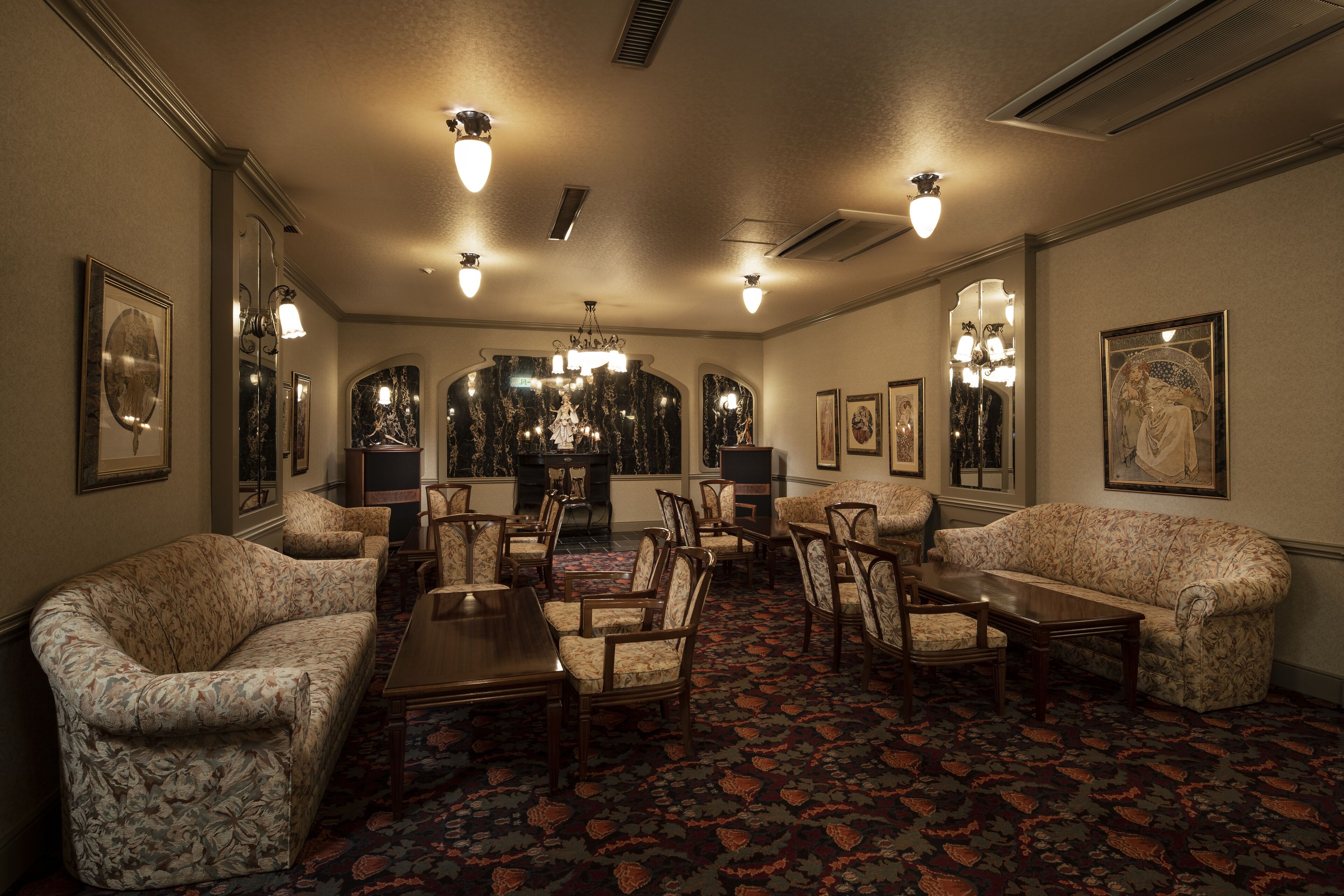 Uma sala de jantar formal com um candelabro, sofás estampados e piso coberto de carpete.