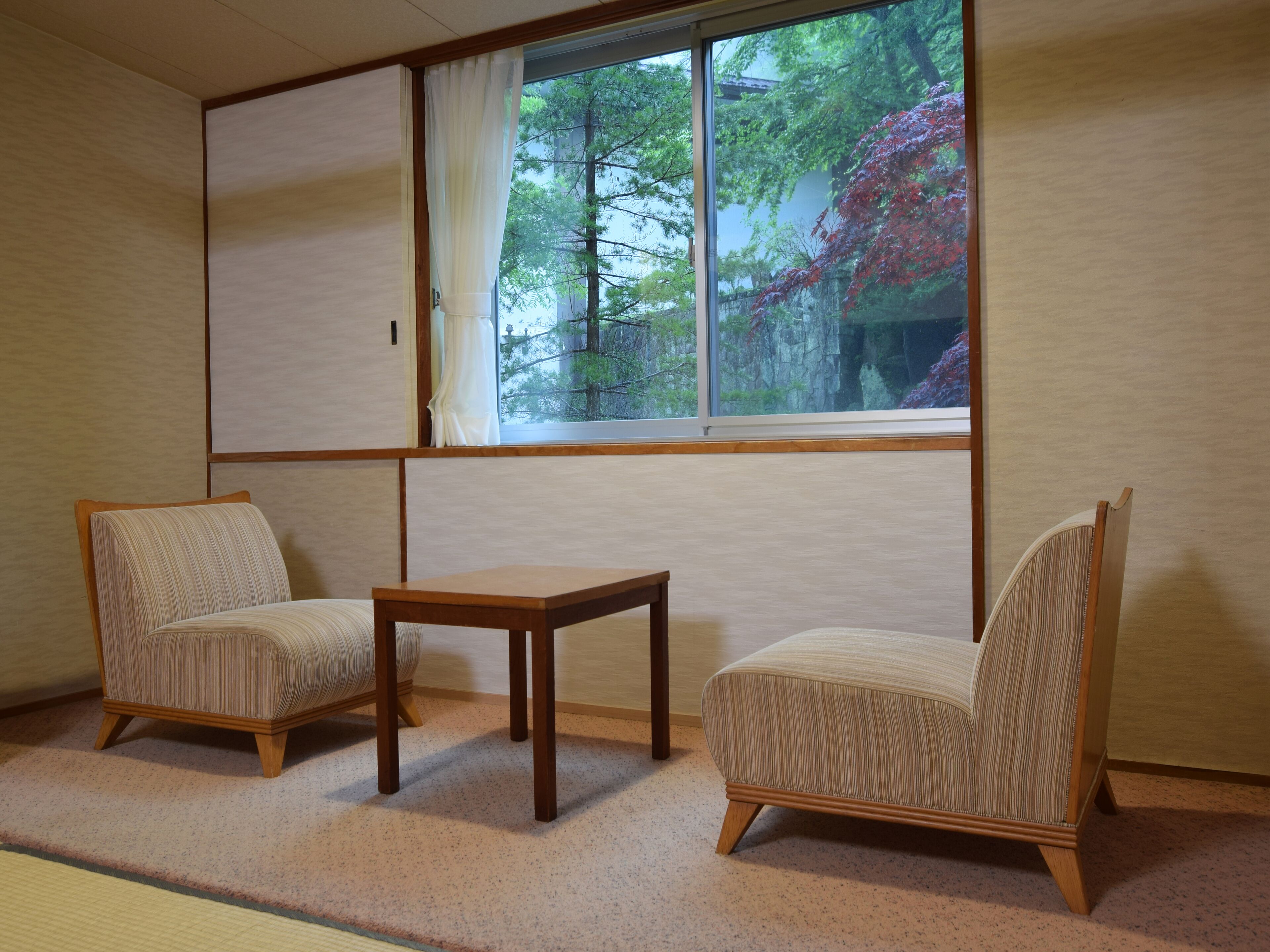 A traditional Japanese room with tatami flooring, two tatami mats, a low wooden table, and a sliding shoji screen.