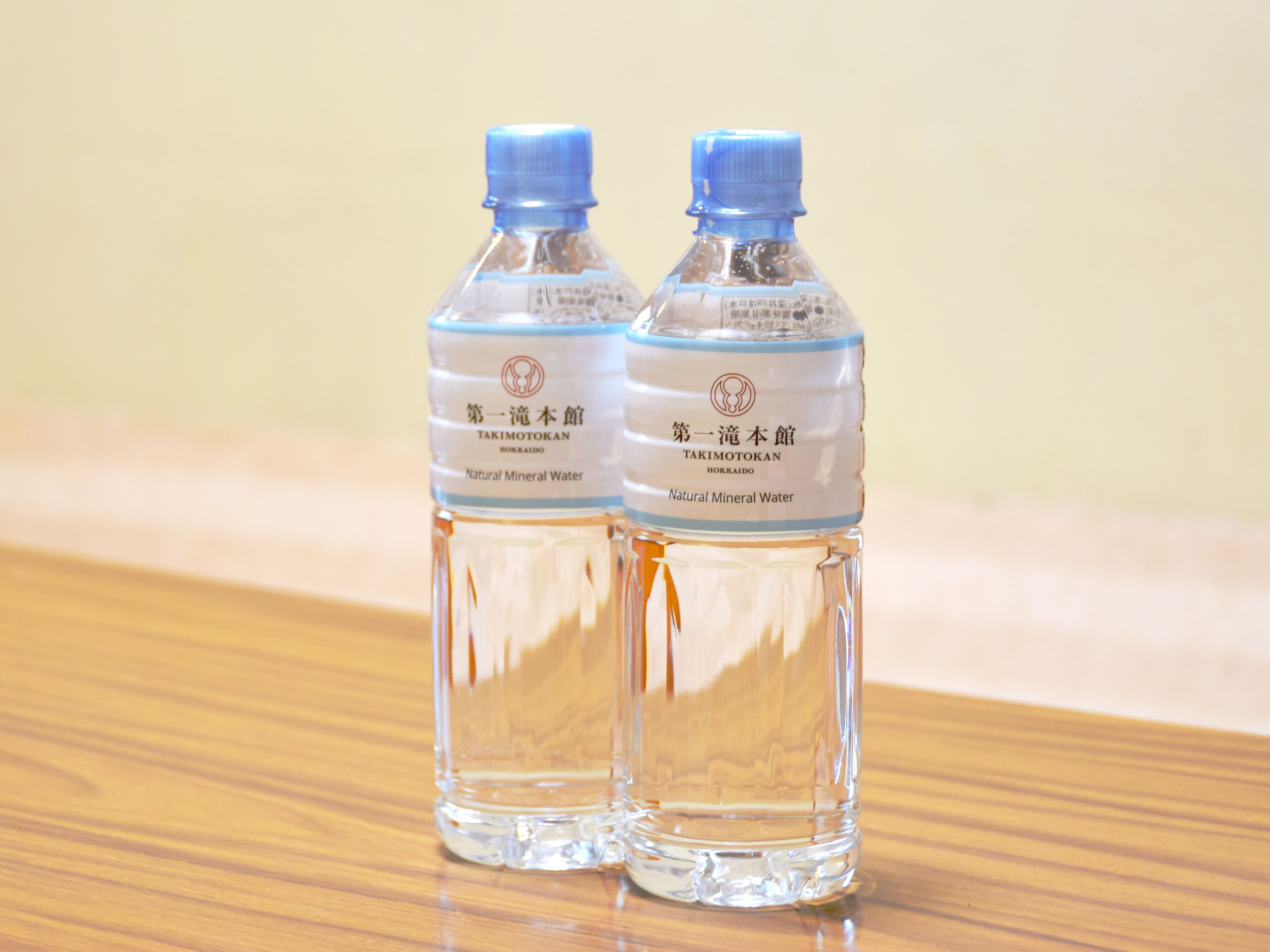Dos botellas de agua con la etiqueta "Takimotokan" sobre una superficie de madera.