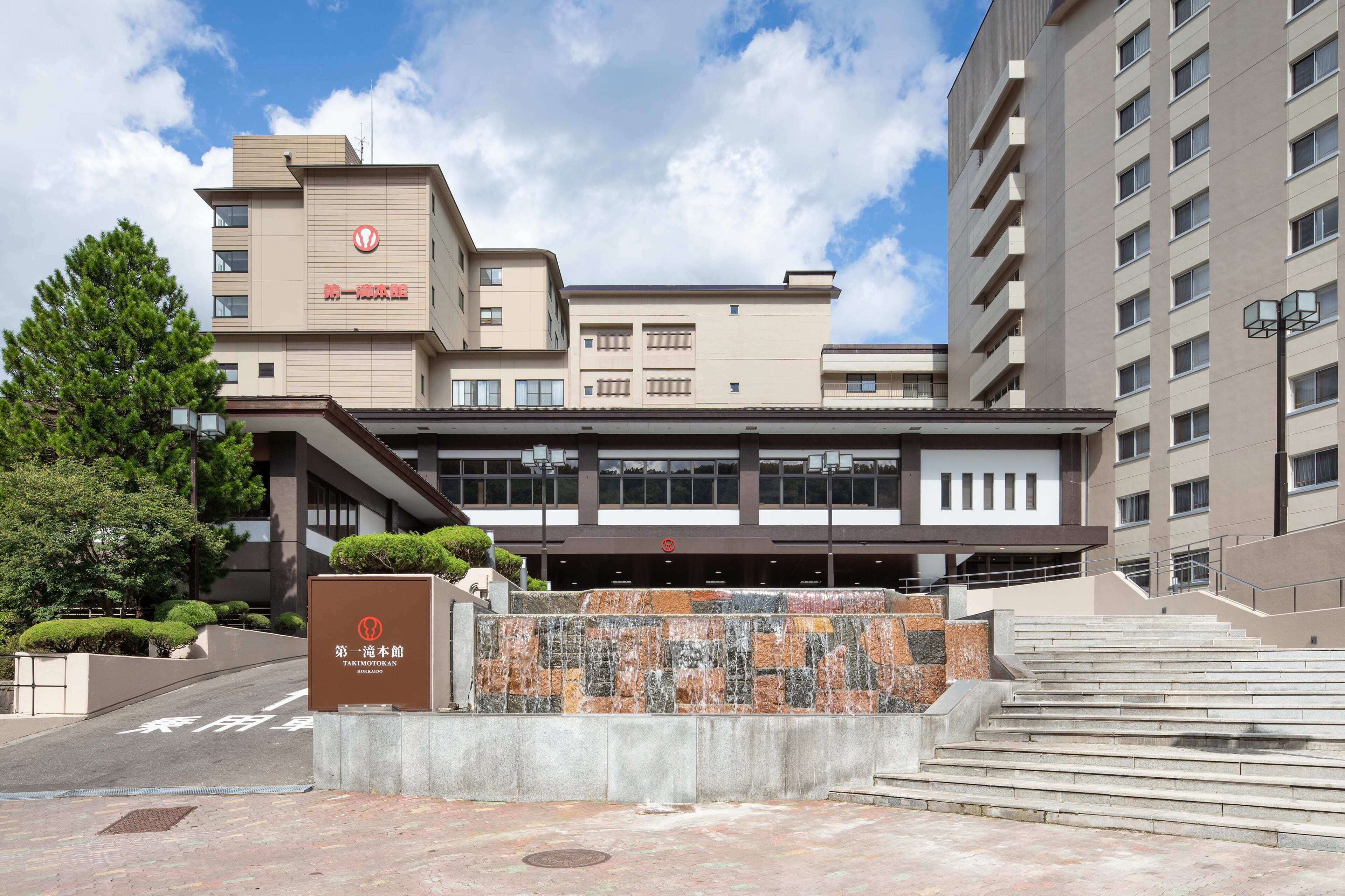 A modern building with a stone facade and a sign indicating it is a hotel.