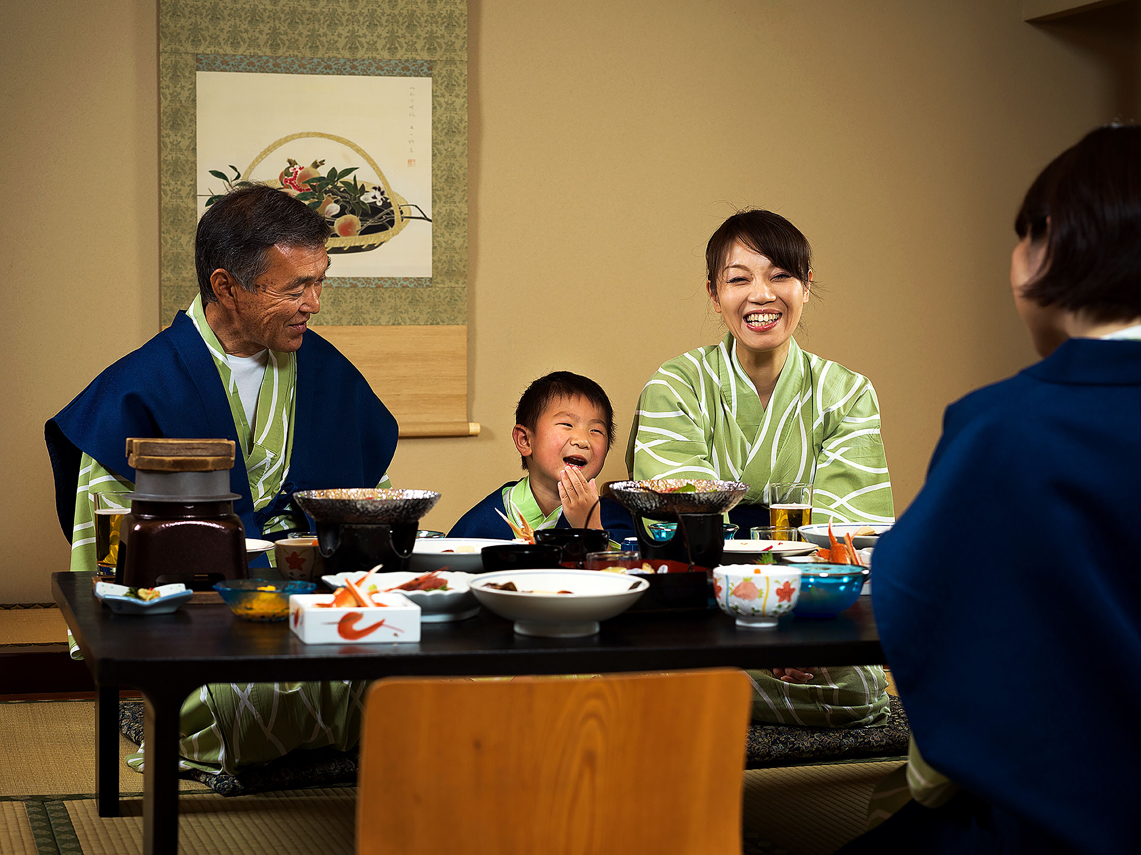 A traditional Japanese meal setting with a table, various dishes, and a painting on the wall.
