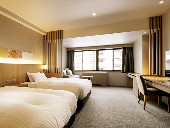 Une chambre d’hôtel avec deux lits, un bureau et une fenêtre donnant sur des immeubles.