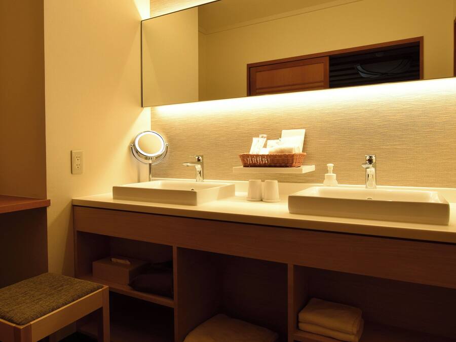 A bathroom with two sinks, a mirror, and a shelf with toiletries.