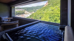 A spa area with a hot tub and a view of a mountainous landscape. - Dai-ichi Takimotokan (Noboribetsu)