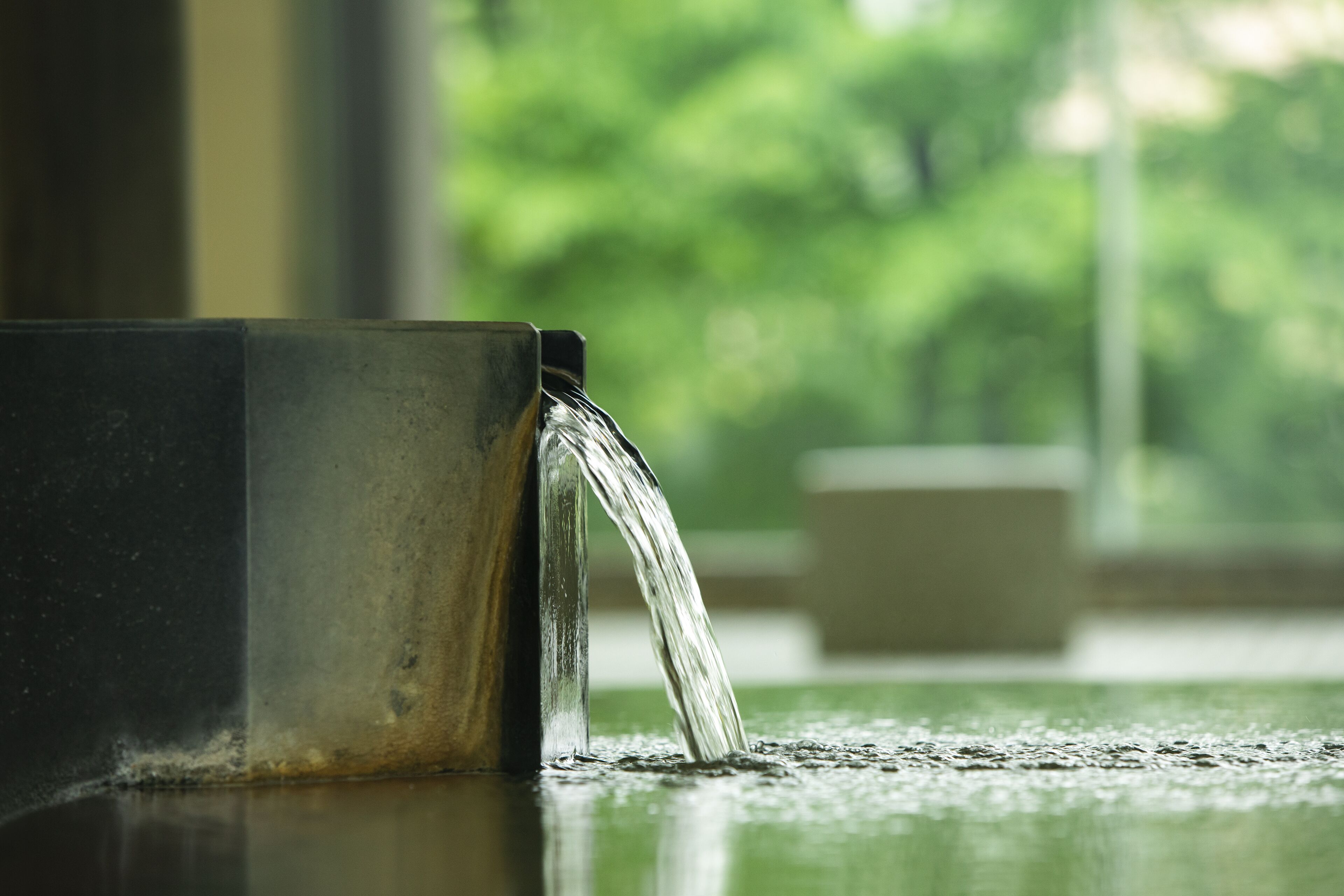 A metal mug with water flowing from its spout.