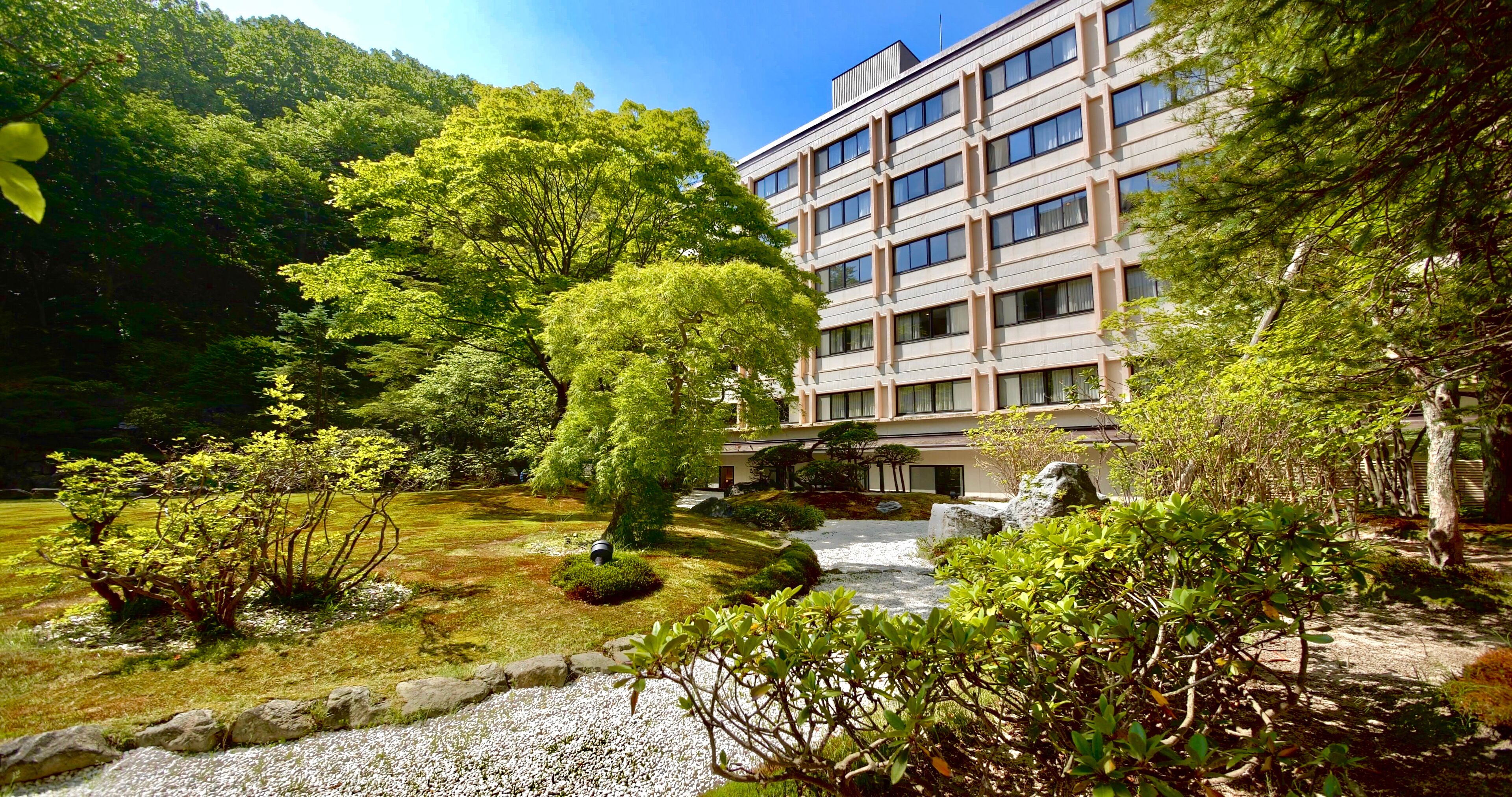 A modern building with a traditional garden, including a koi pond and various trees.