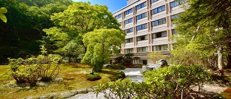 A modern building with a traditional garden, including a koi pond and various trees.