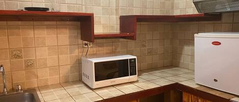 Cocina pequeña equipada con microondas, fregadero y refrigerador.