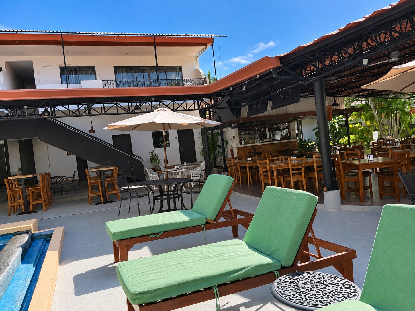 Un espace extérieur aménagé avec des fauteuils et des tables, une piscine et un bar.