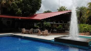 Una piscina al aire libre, sillones reclinables de piscina