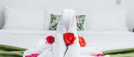 A neatly made bed with white linens and red roses.