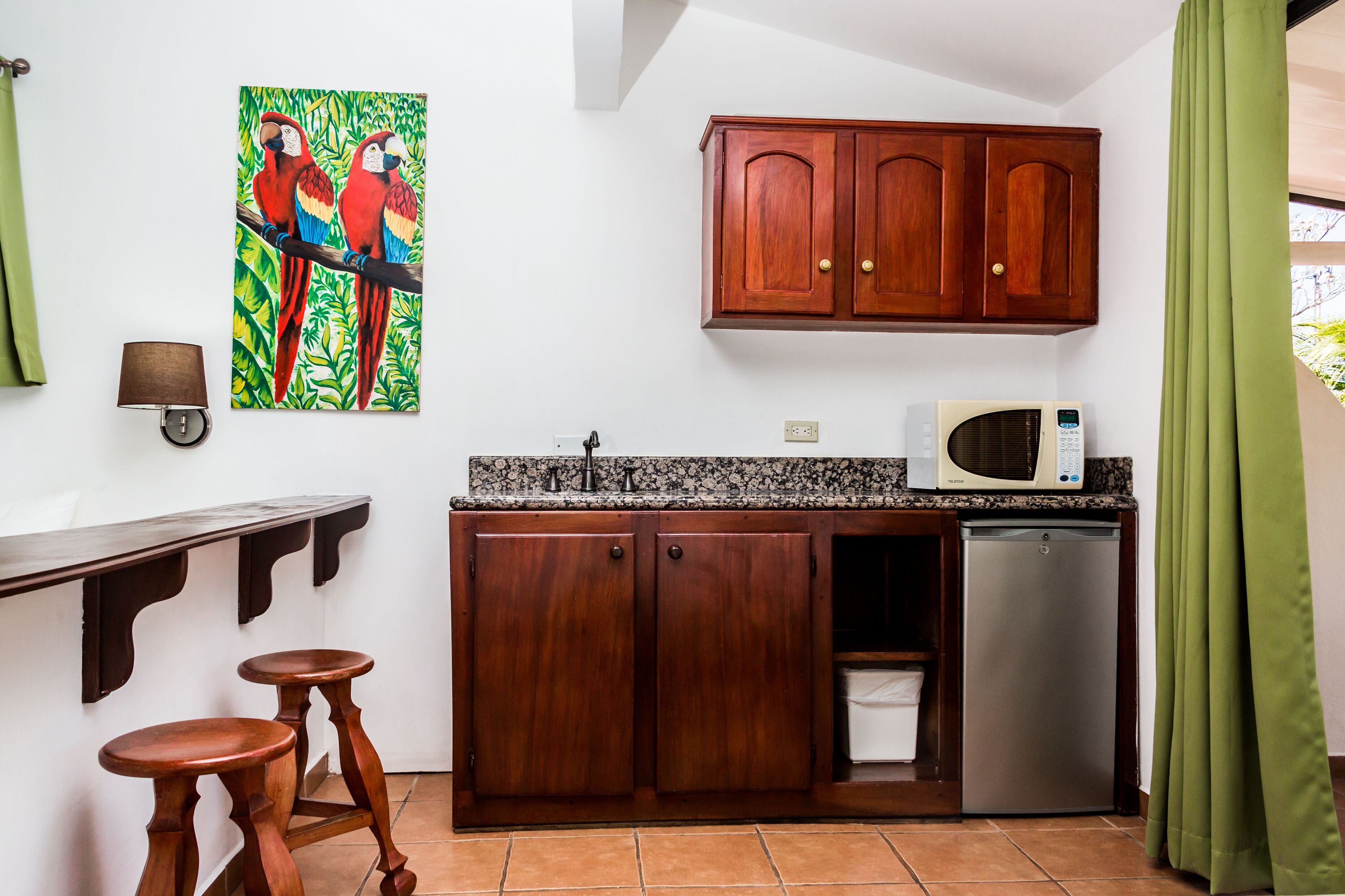 Una cocina compacta con armarios de madera, un microondas y un refrigerador pequeño.