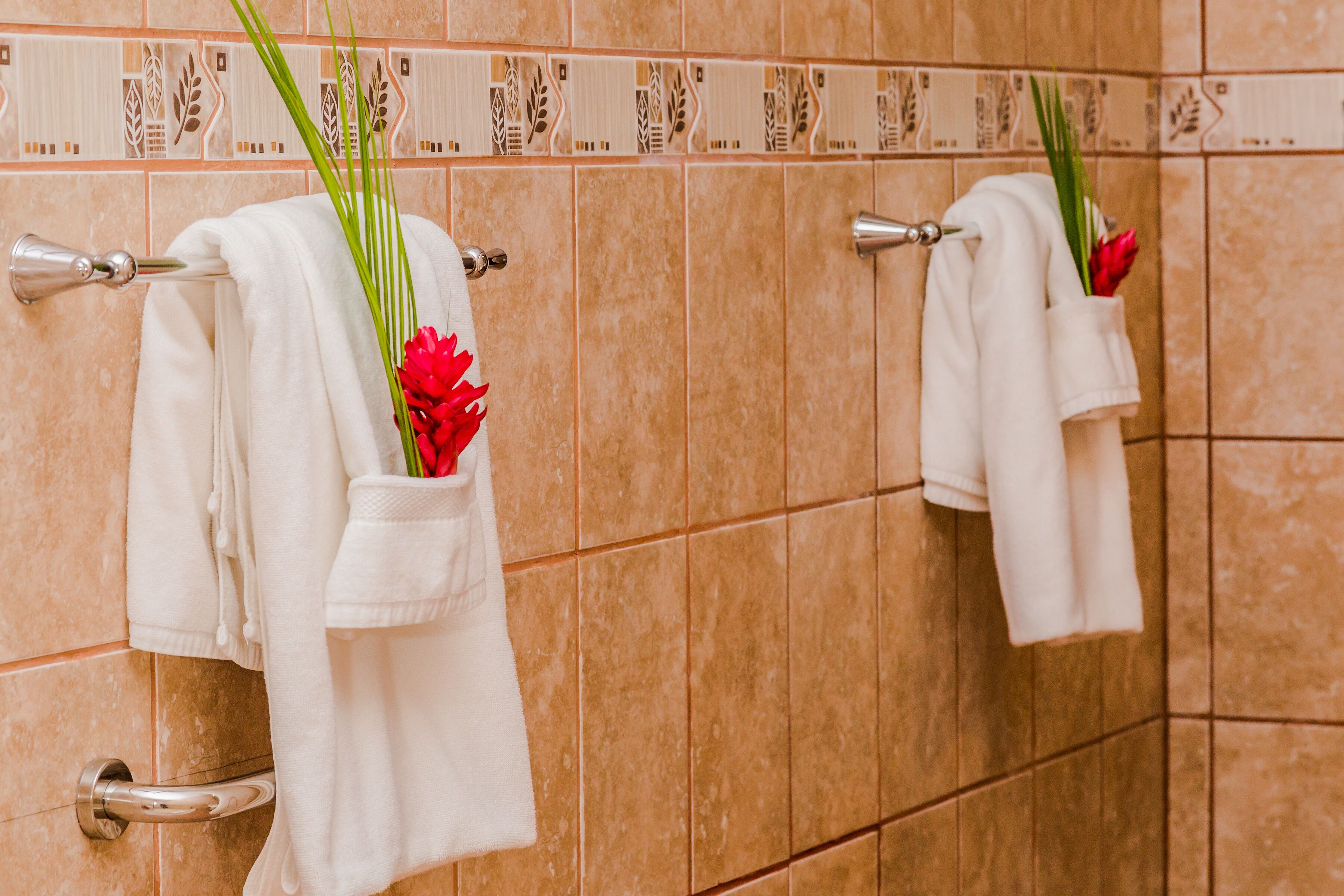 A bathroom with beige tiles and towels hanging on metal towel racks.