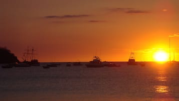 Un atardecer sobre un mar tranquilo con varios barcos.