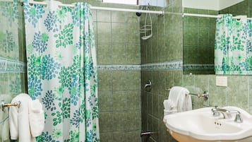 A bathroom with a shower curtain, a sink, and a mirror.