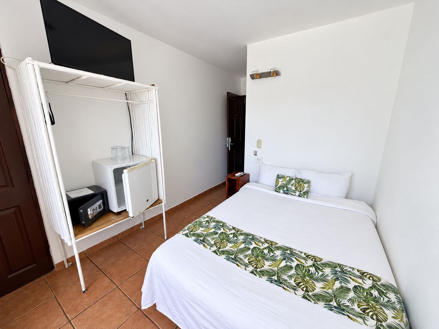 Ein Hotelzimmer mit einem Bett, einem weißen Baldachin, einem kleinen Tisch mit einem Radio und einer Wandleuchte.
