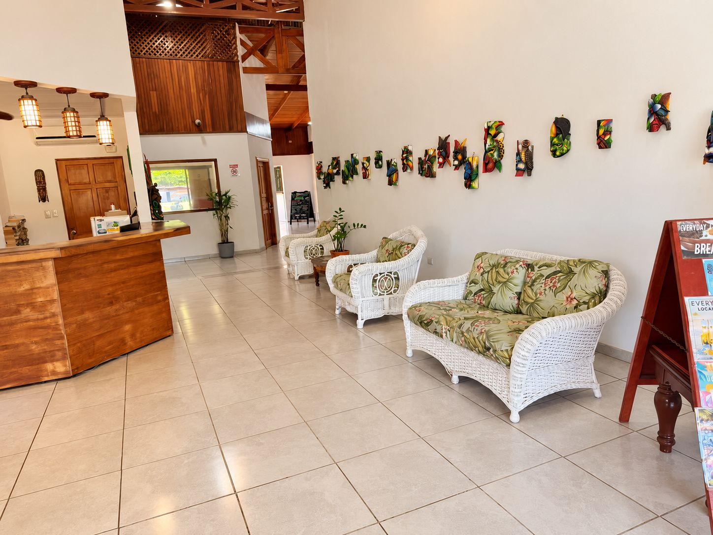 A reception area with a wooden counter, white wicker furniture, and a wall decorated with colorful artwork.