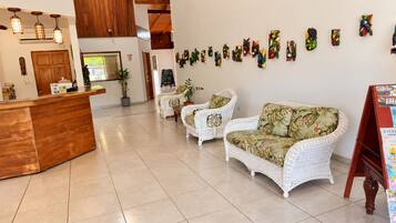 A reception area with a wooden counter, white wicker furniture, and a wall decorated with colorful artwork.