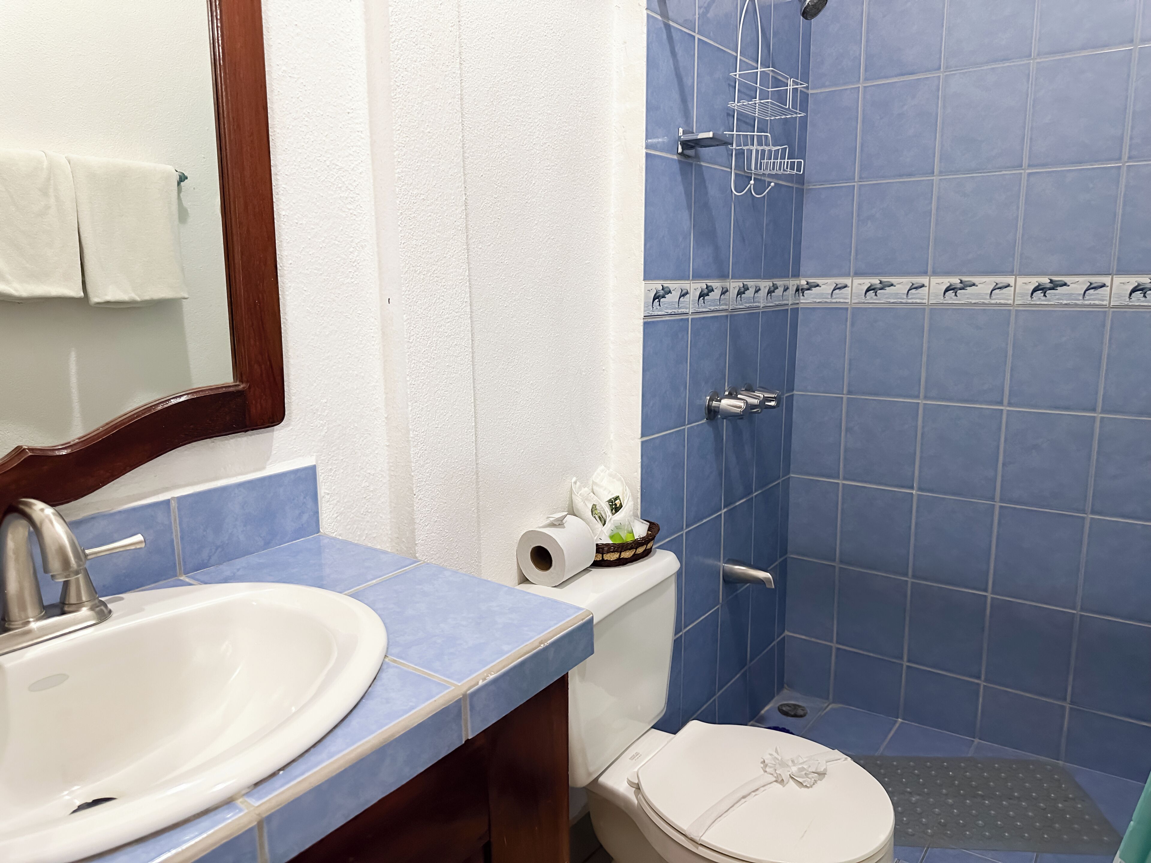 Un baño con un lavabo blanco, azulejos azules, un inodoro y una zona de ducha.