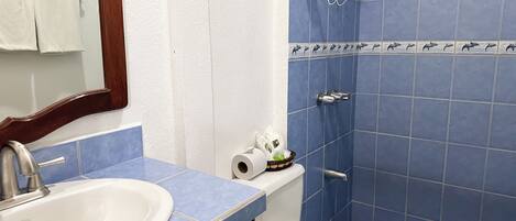 Un baño con un lavabo blanco, azulejos azules, un inodoro y una zona de ducha.